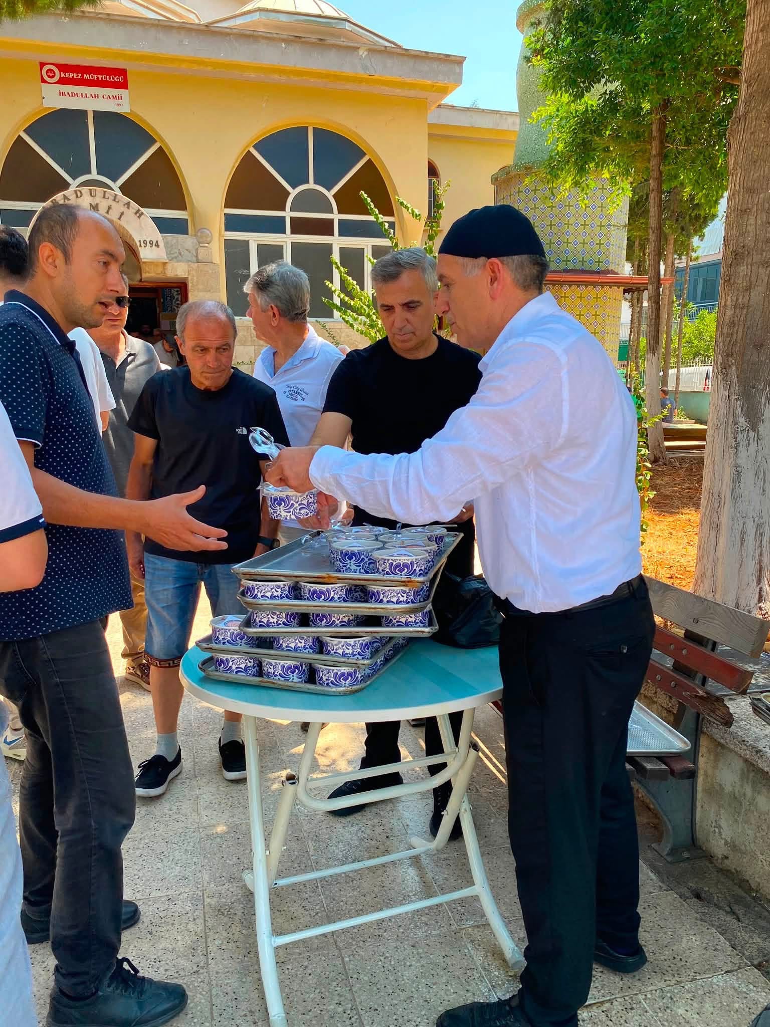 Başkan Ekrem Keskin cemaate aşure ikram ederken